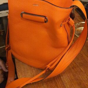 Sac à main seau Lancel modèle Huit en cuir orange contemporain avec accessoires dorés